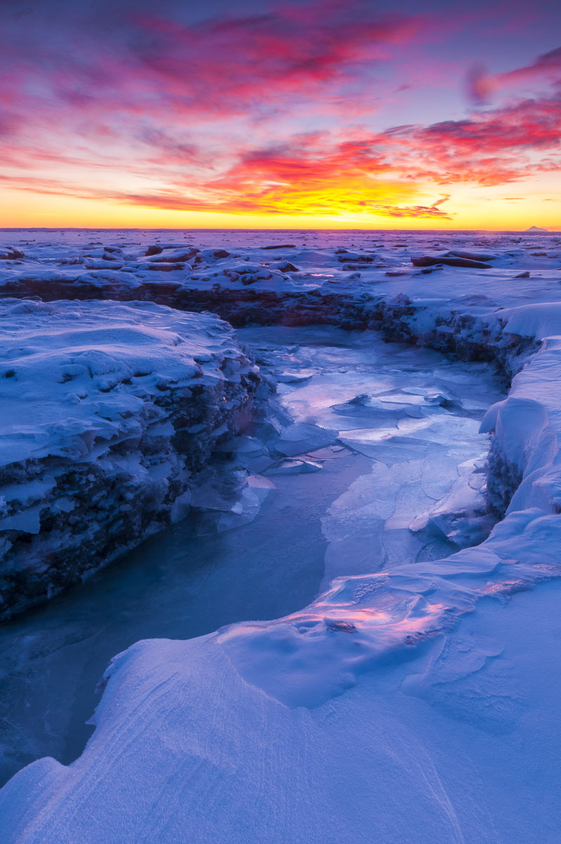 The outflow of Rabbit Creek cuts through the frozen mudflats in the Anchorage Coastal Wildlife Refuge in winter.