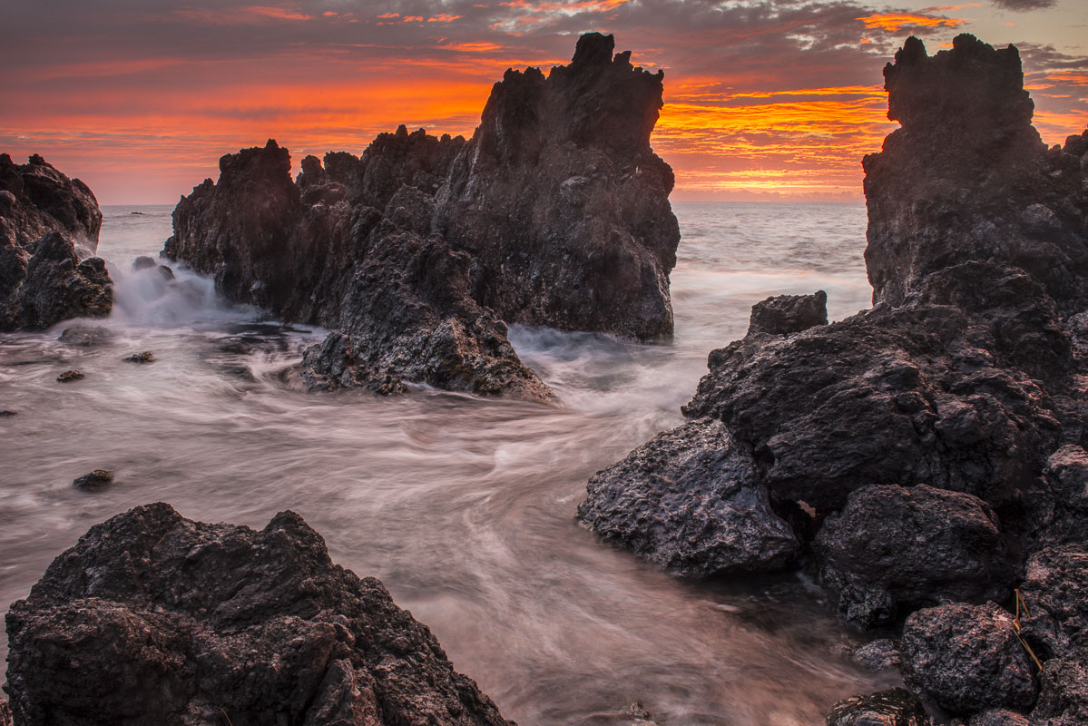 The colors of sunrise behind coastal lava rocks at Laupahoehoe, Hawaii.
