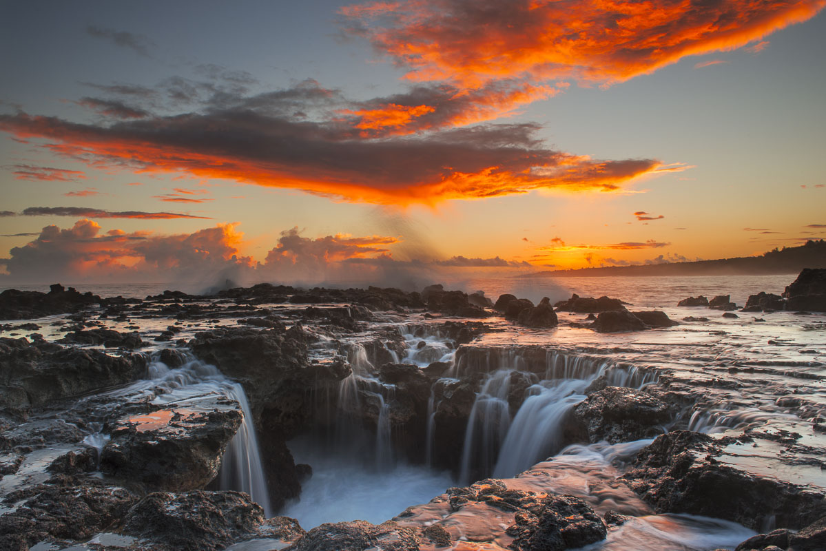 Surf spills into a hole in a rock outrcop at sunrise on the east side of Kauai, Hawaii.