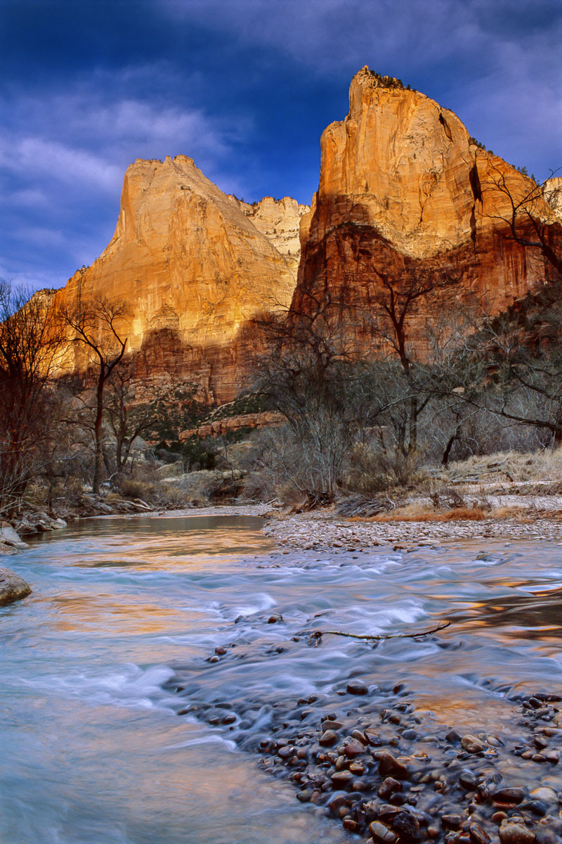 Morning light strikes the canyon walls, reflecting colors onto the Virgin River in Zion National Park, Utah, in winter.