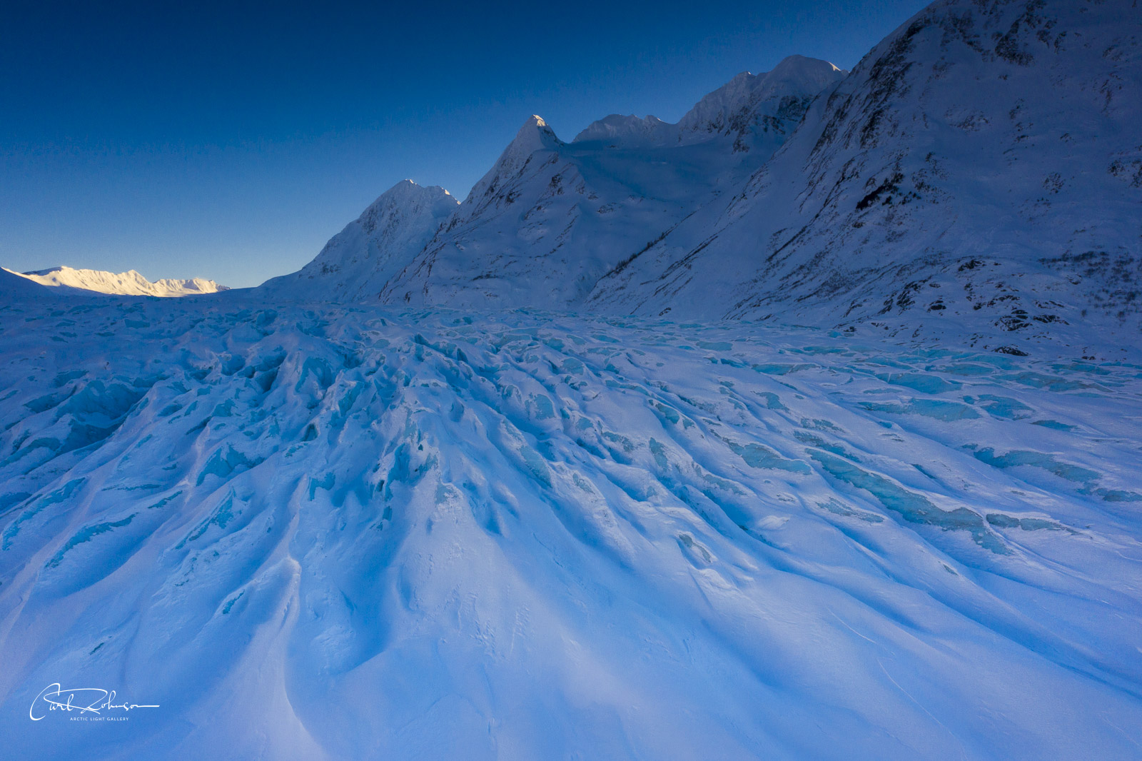 The Spencer Glacier takes on a deep, blue hue in the shade as the day's light drops low on the horizon.
