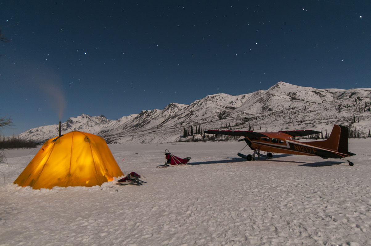 Nighttime view of a base camp on the North Fork of the Koyukuk River in Gates of the Arctic National Park, with dog sled and...
