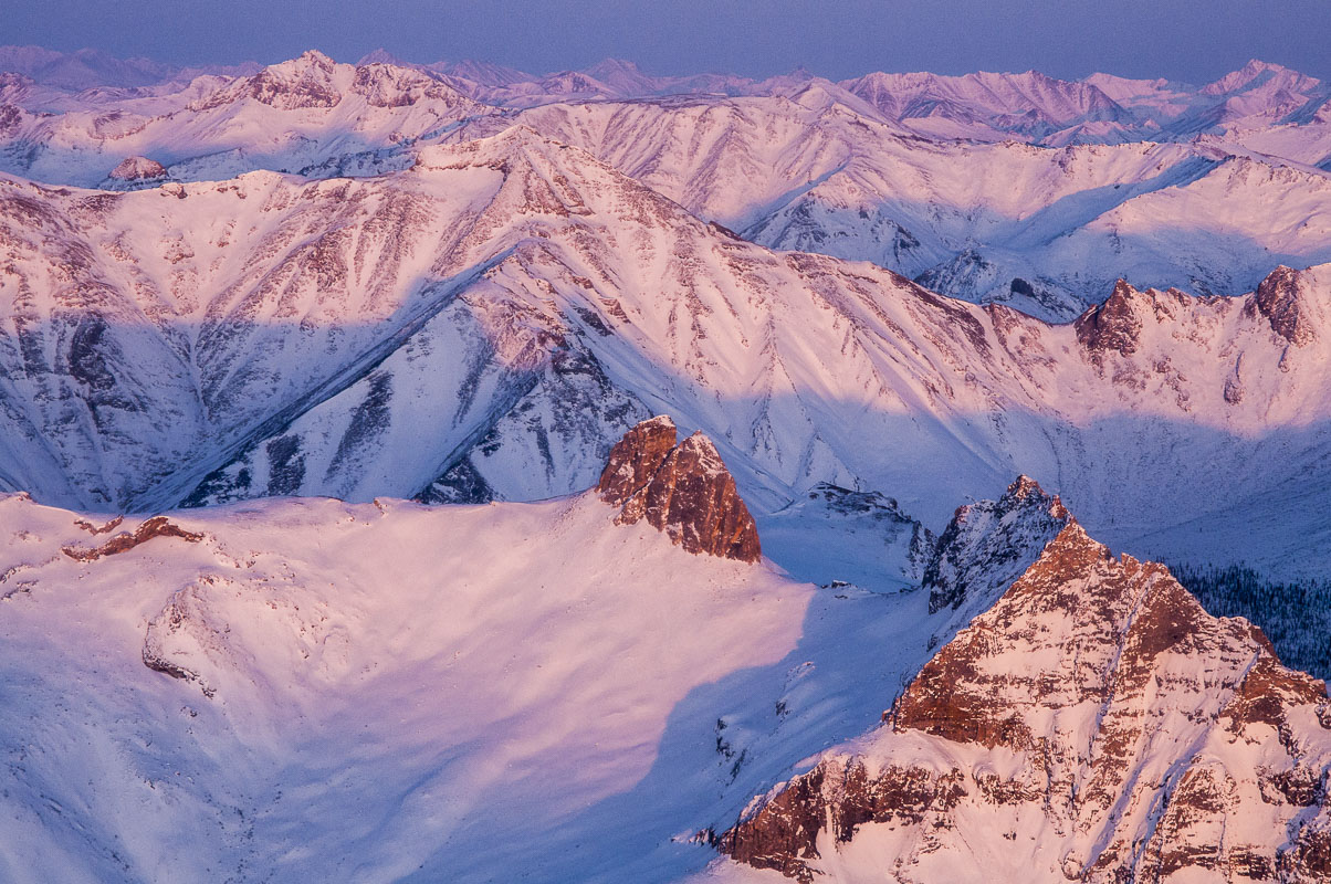 Aerial view of pink alpenglow spreading across ridges of the Brooks Range near the John River.