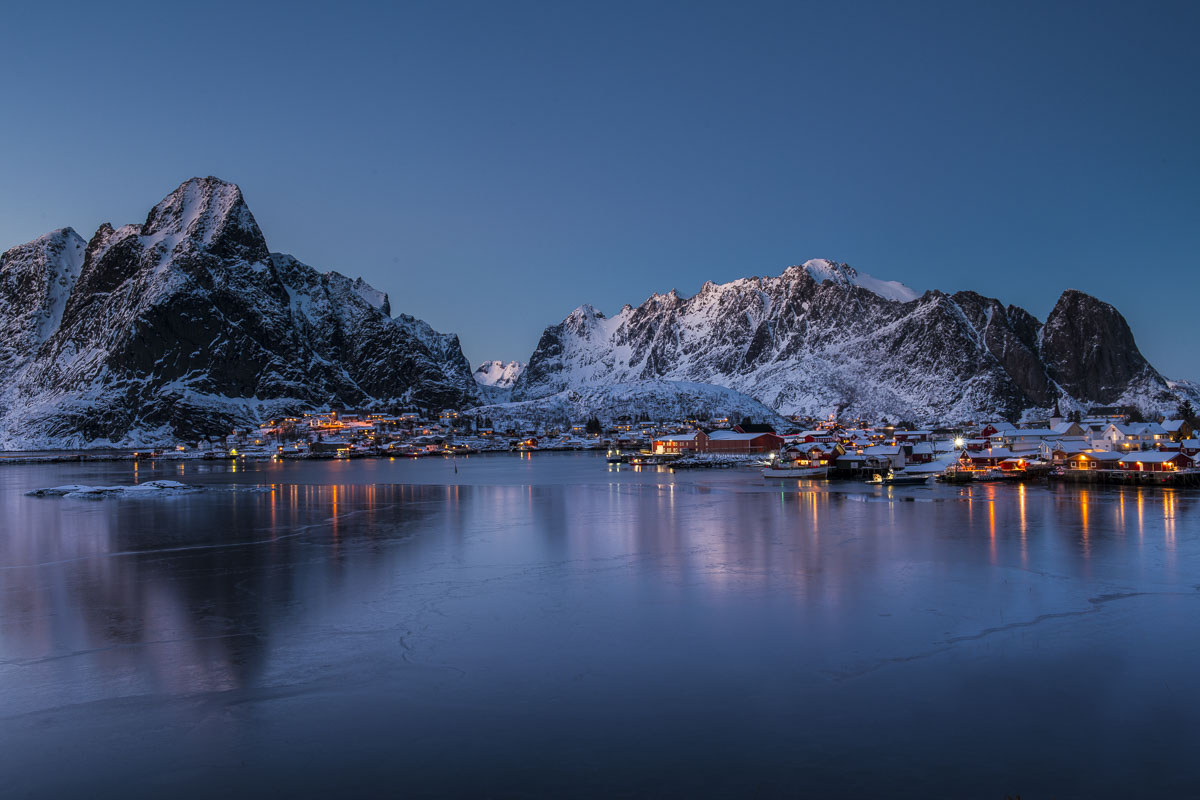 Village lights create pops of warm light as twilight descends upon the village of Reine in the Lofoten Islands, Norway.