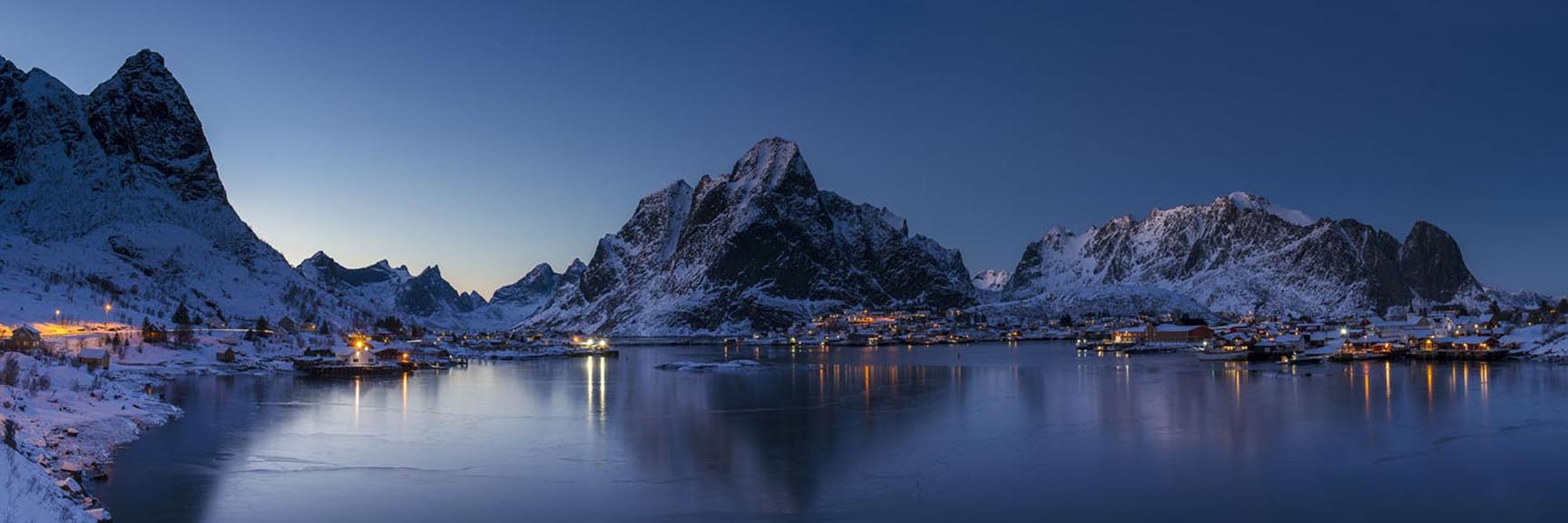 Village lights create pops of warm light as twilight descends upon the village of Reine in the Lofoten Islands, Norway.