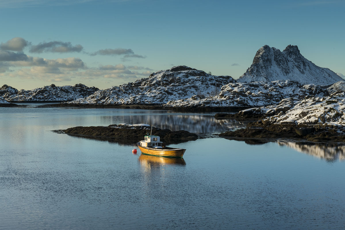 An anchored boat catches morning light in a series of islands near Steine, Norway.