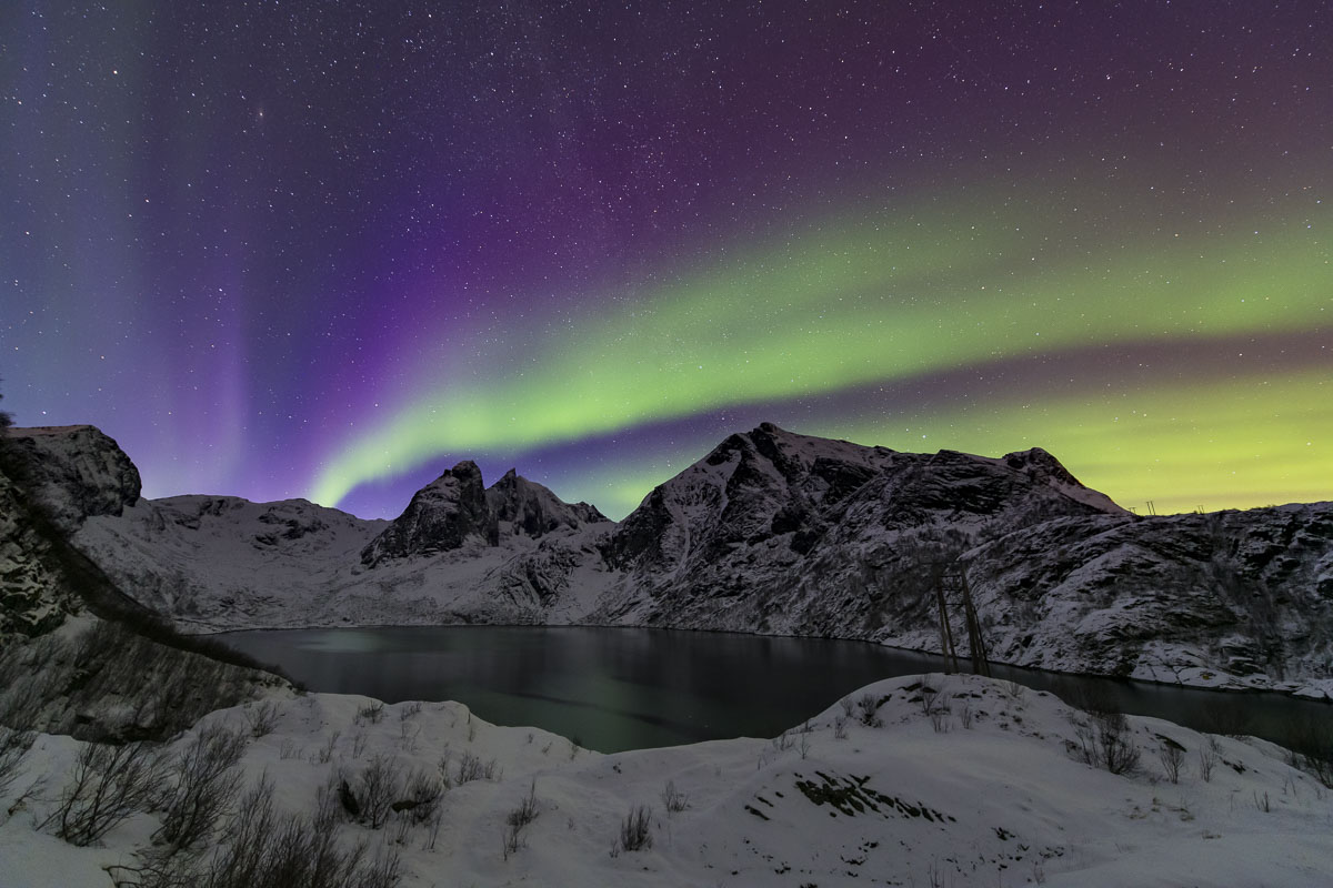 The aurora borealis glows over Djupfjorden in the Lofoten Islands, Norway.