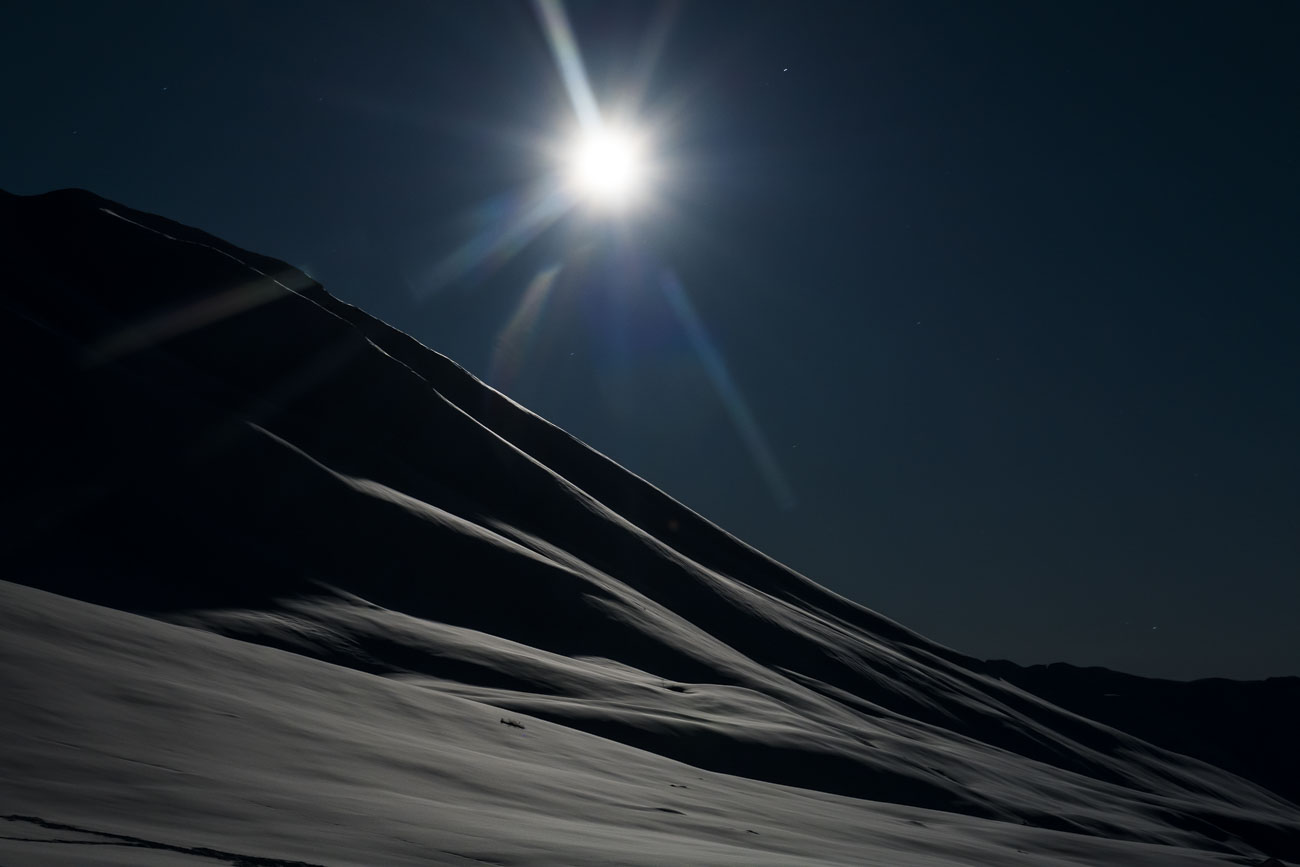 A bright moon hovers over a mountain ride in the Talkeetna Mountains in the Hatcher Pass Management Area, Alaska.