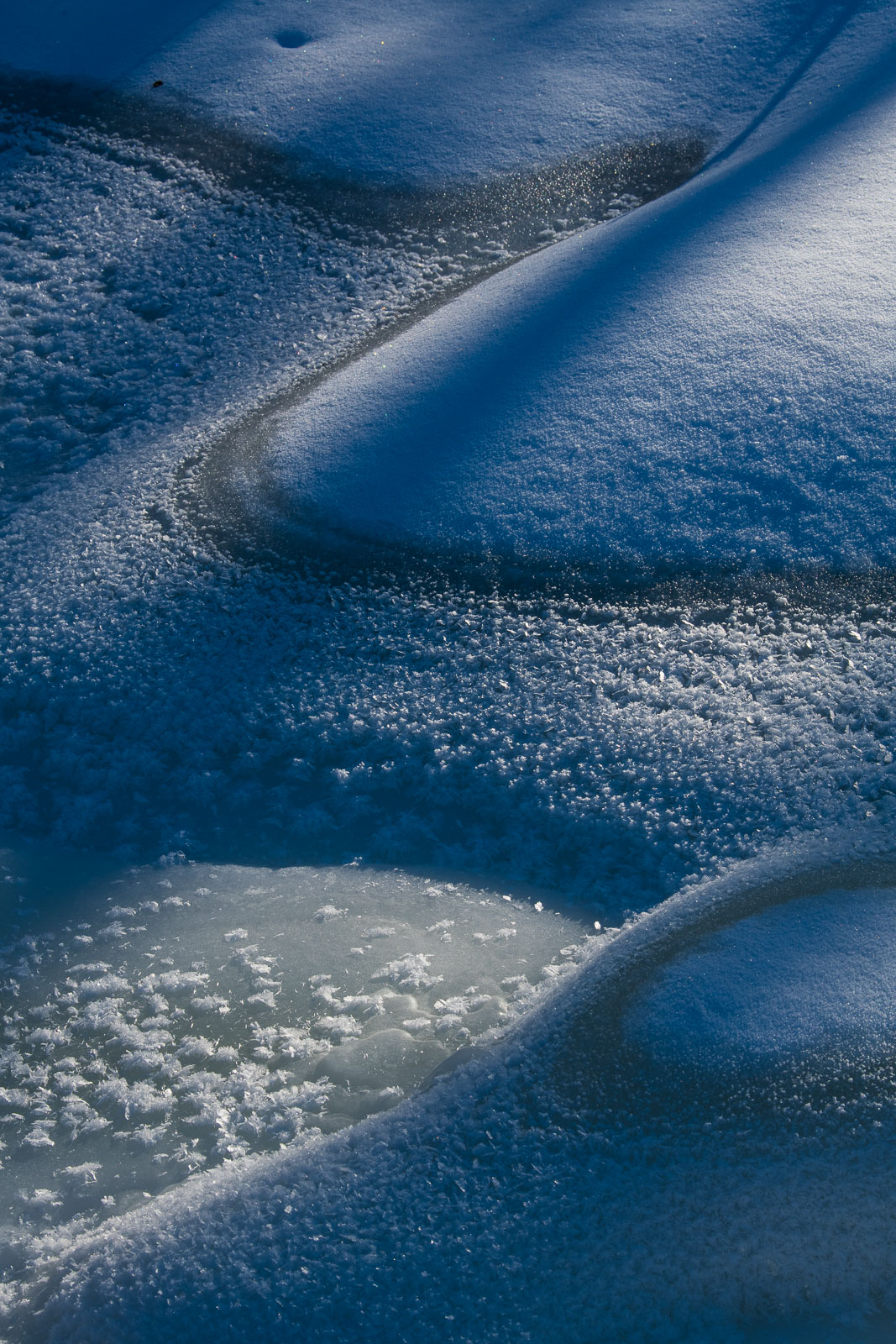 Light and shadow play with patterns of ice and snow on a frozen creek in Wiseman, Alaska.
