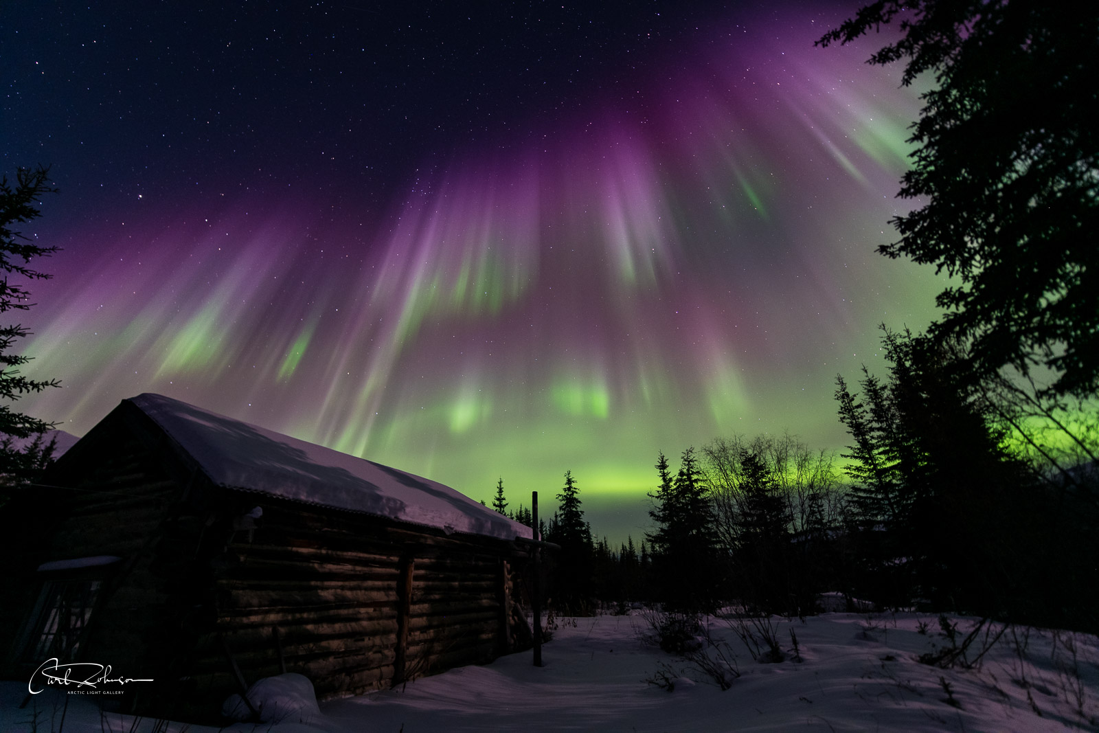 The aurora borealis fills the sky over the Kalhabuk Memorial Chapel in Wiseman, Alaska.