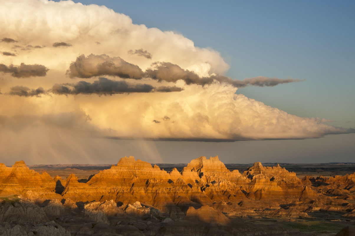 A summer rain storm hovers over formations in  Cedar Pass, Badlands National Park, South Dakota.