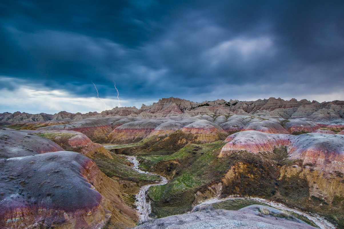 Two bolts of lightning strike the ground from a thunderstorm cloud in the Conata Basin, Badlands National Park, South Dakota....