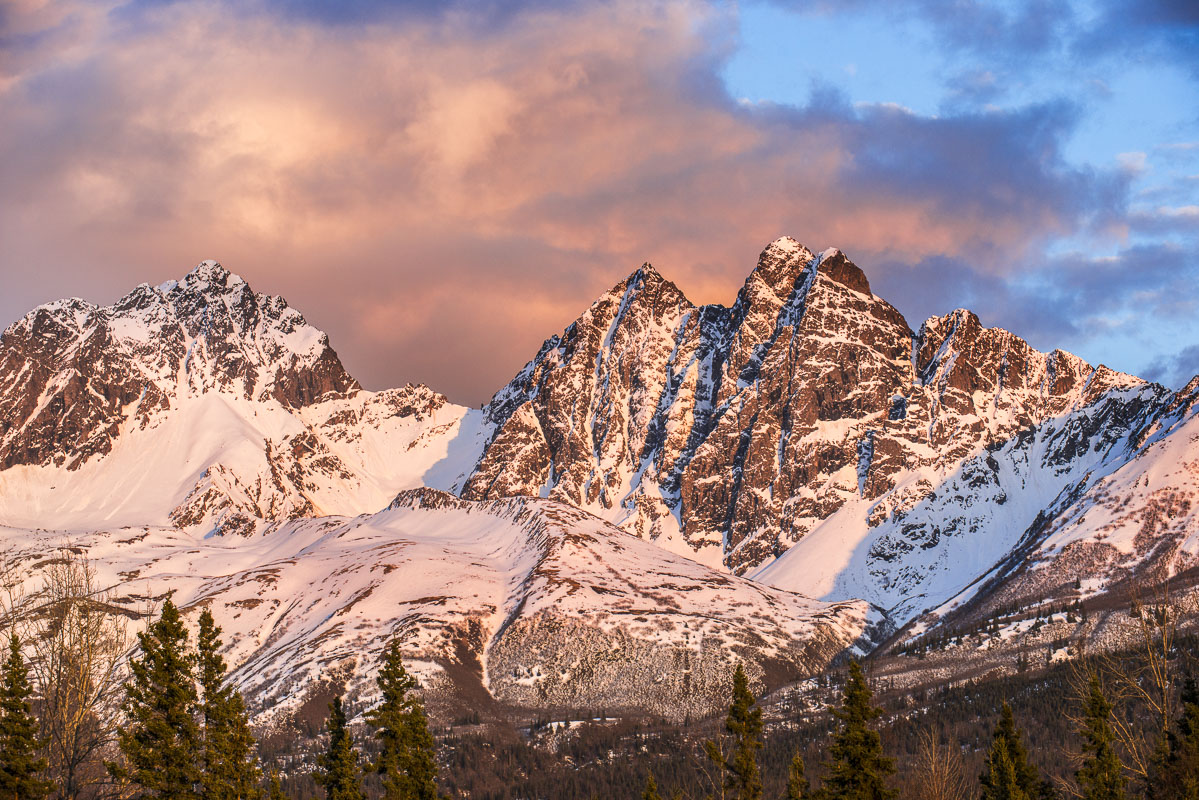 Evening light falls on Twin Peaks in the Chugach Mountains in spring, with Pioneer Peak in the background.