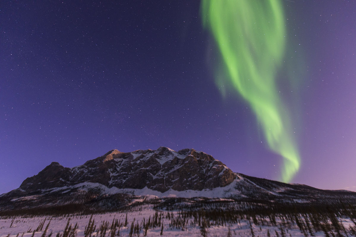 Aurora borealis over Mt. Sukakpak in the Brooks Range in early autumn, with a bright moon lighting up the sky.