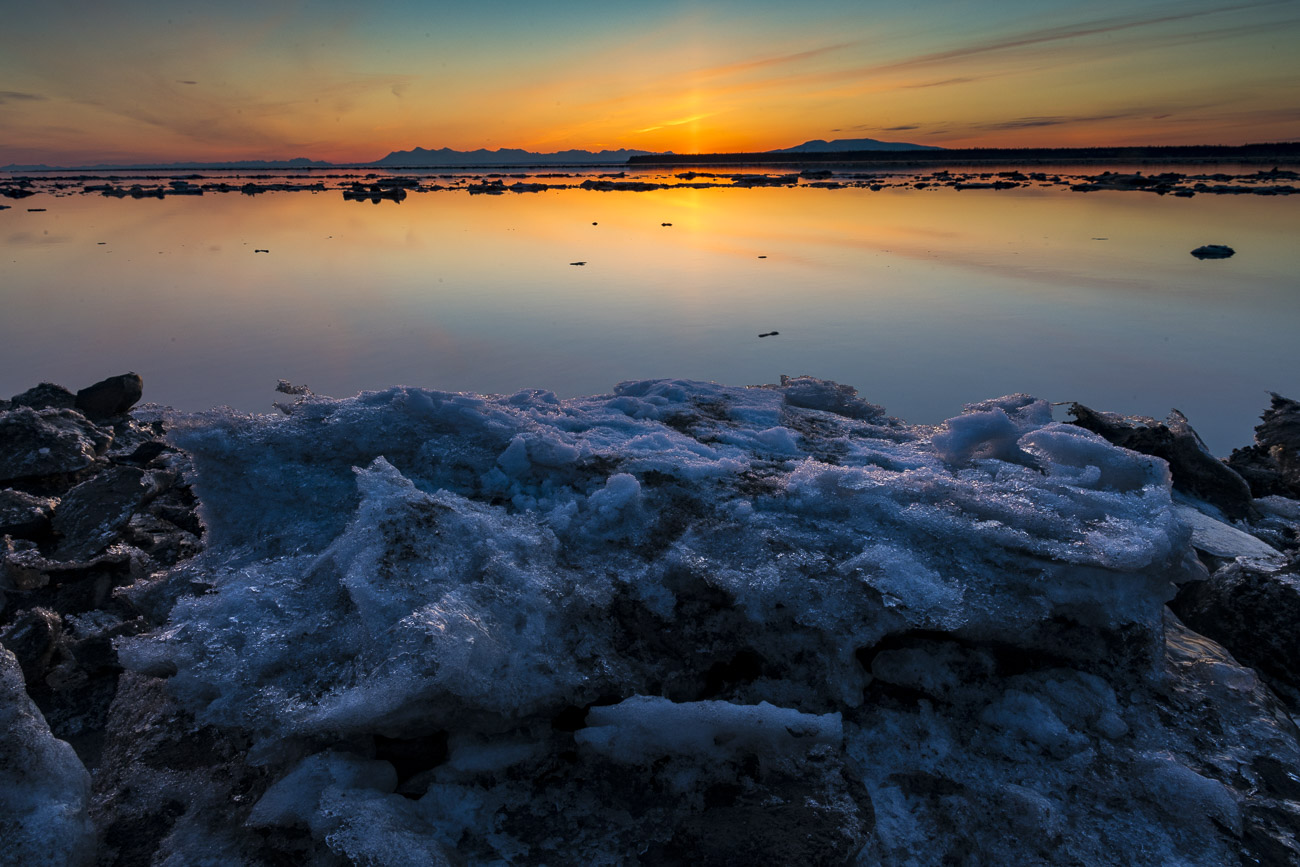 Ice plates from the last high tide pile up along the shores of Cook Inlet as the sun sets in spring.