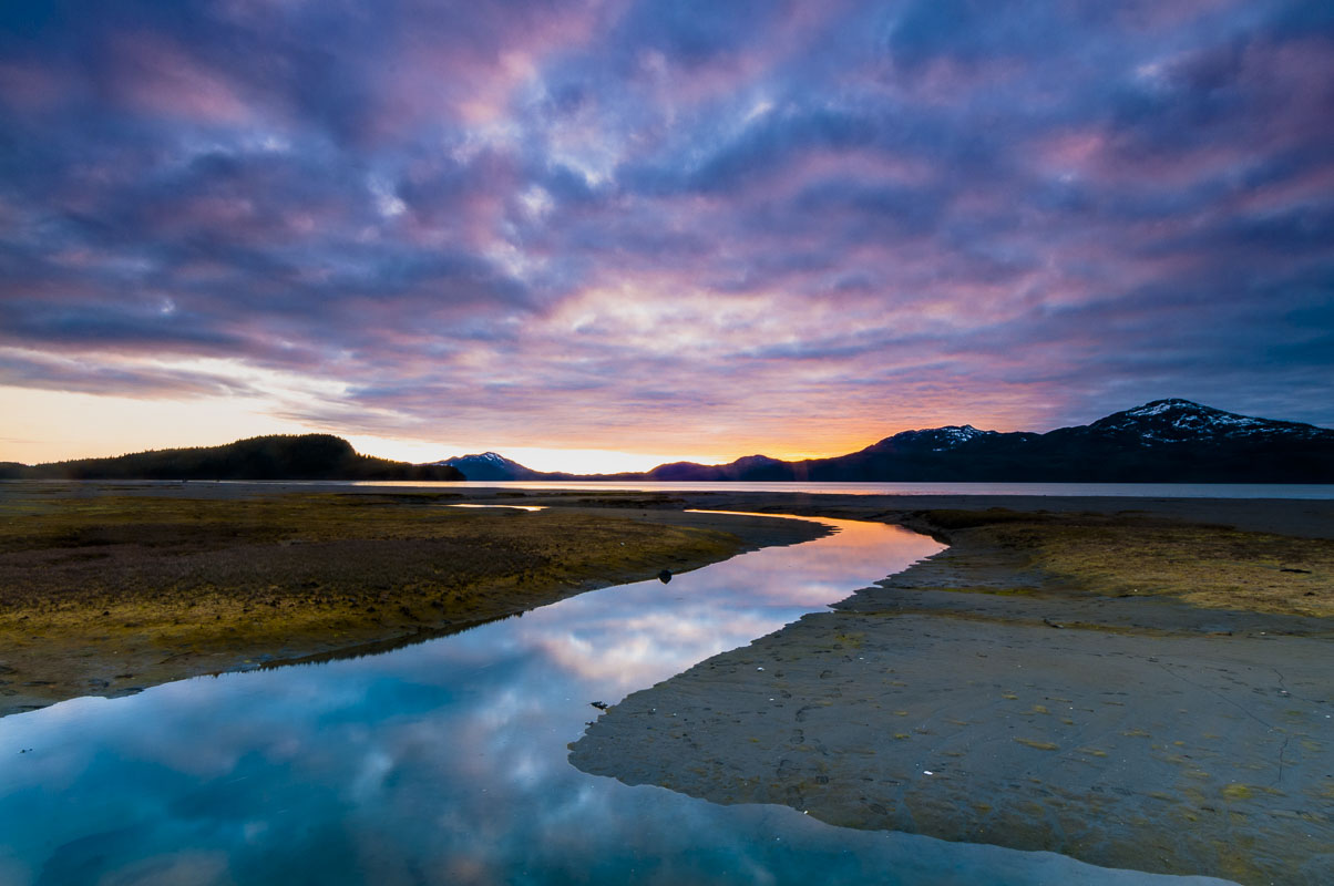 Sunset brightens up and adds color to clouds over the mouth of Hartney Creek as it spills into Hartne Bay, Chugach National Forest...