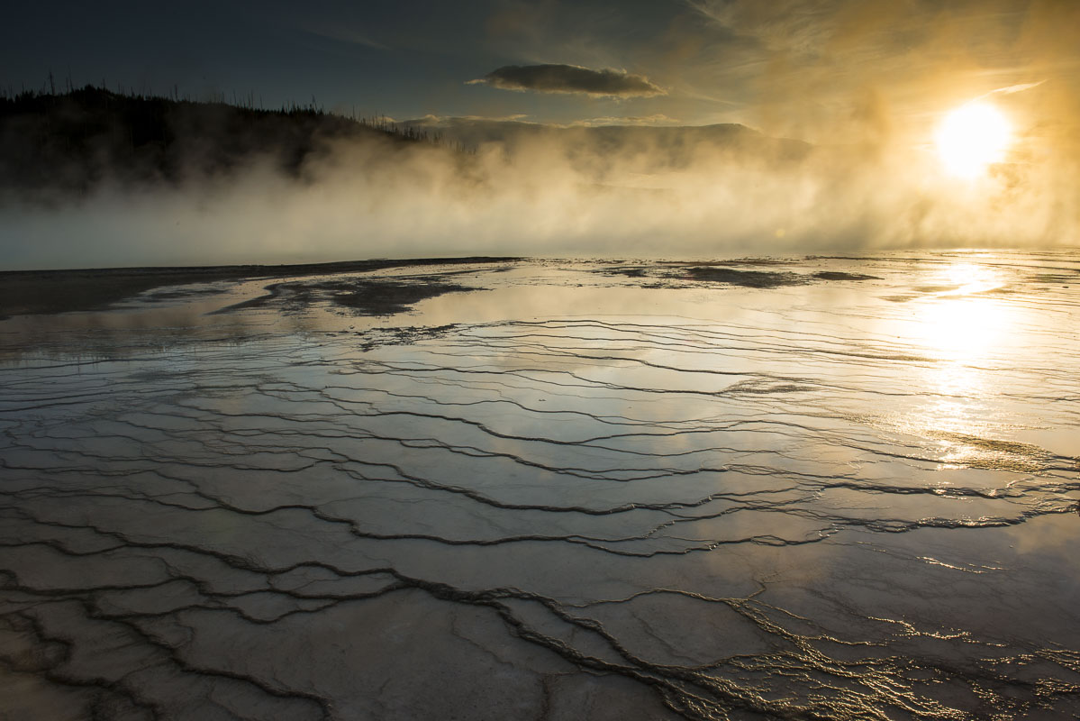 Evening light shines through the steam rising over the Grand Prismatic Spring in Yellowstone National Park, Wyoming.