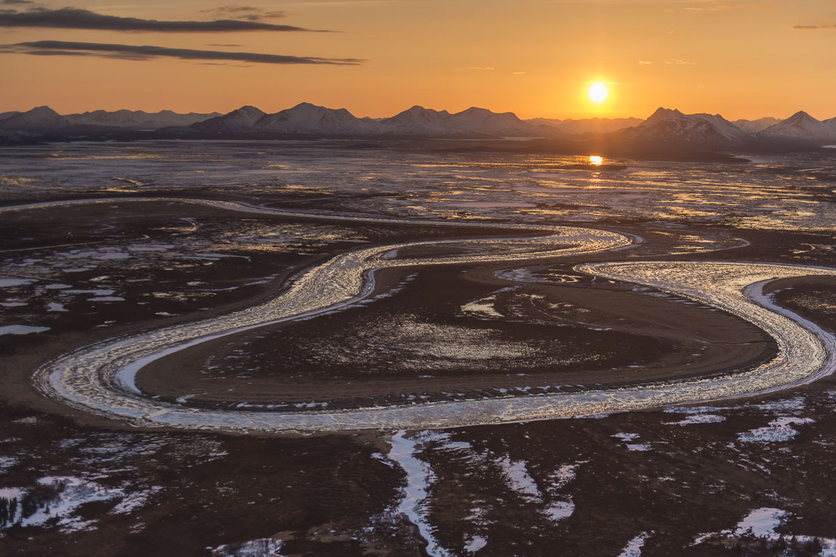 The sun sets behind the Wood River Mountains in early May, while a partially-frozen Snake River winds its way through the Togiak...