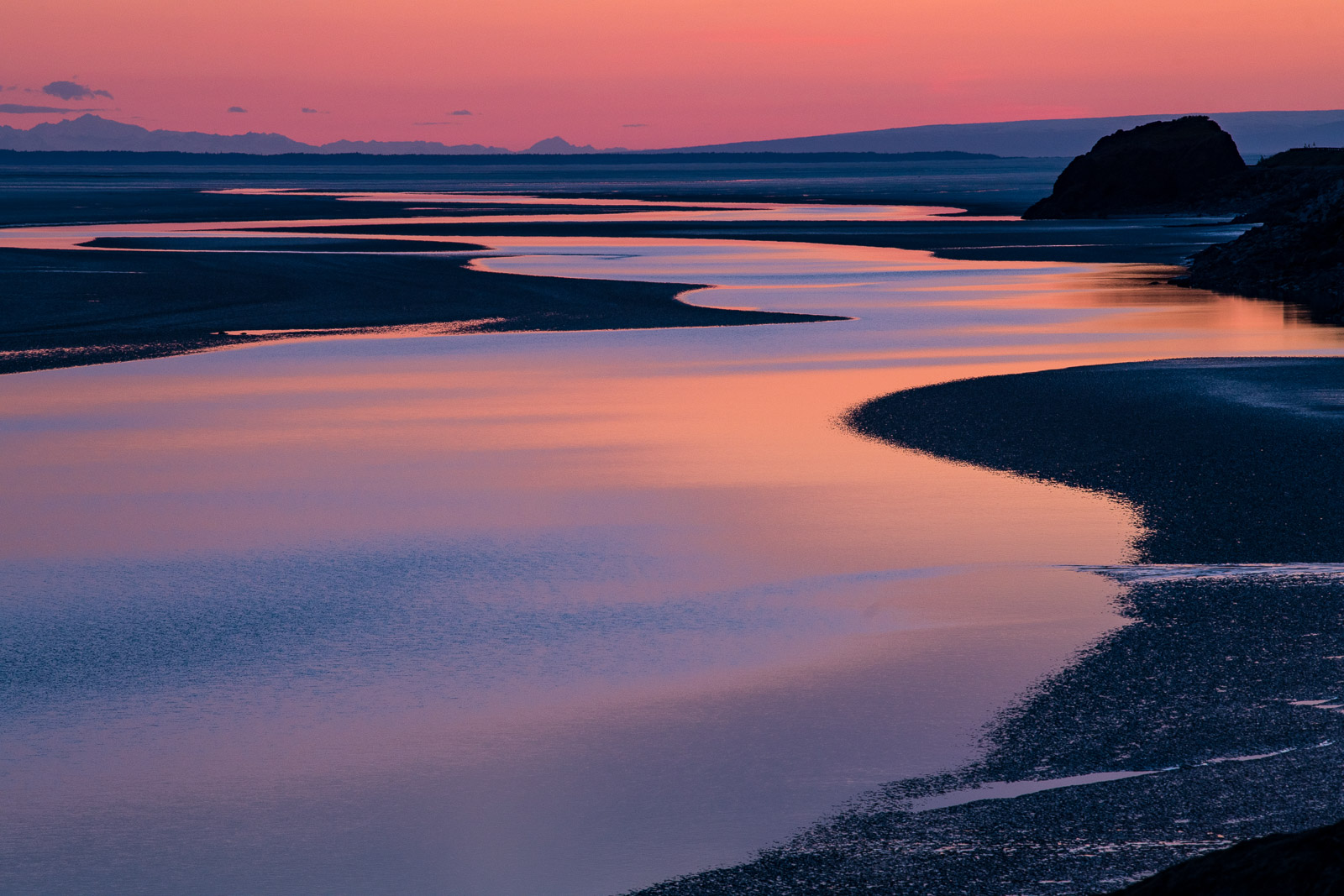 Post-sunset colors light up the sky and waters of the Turnagain Arm at low tide.