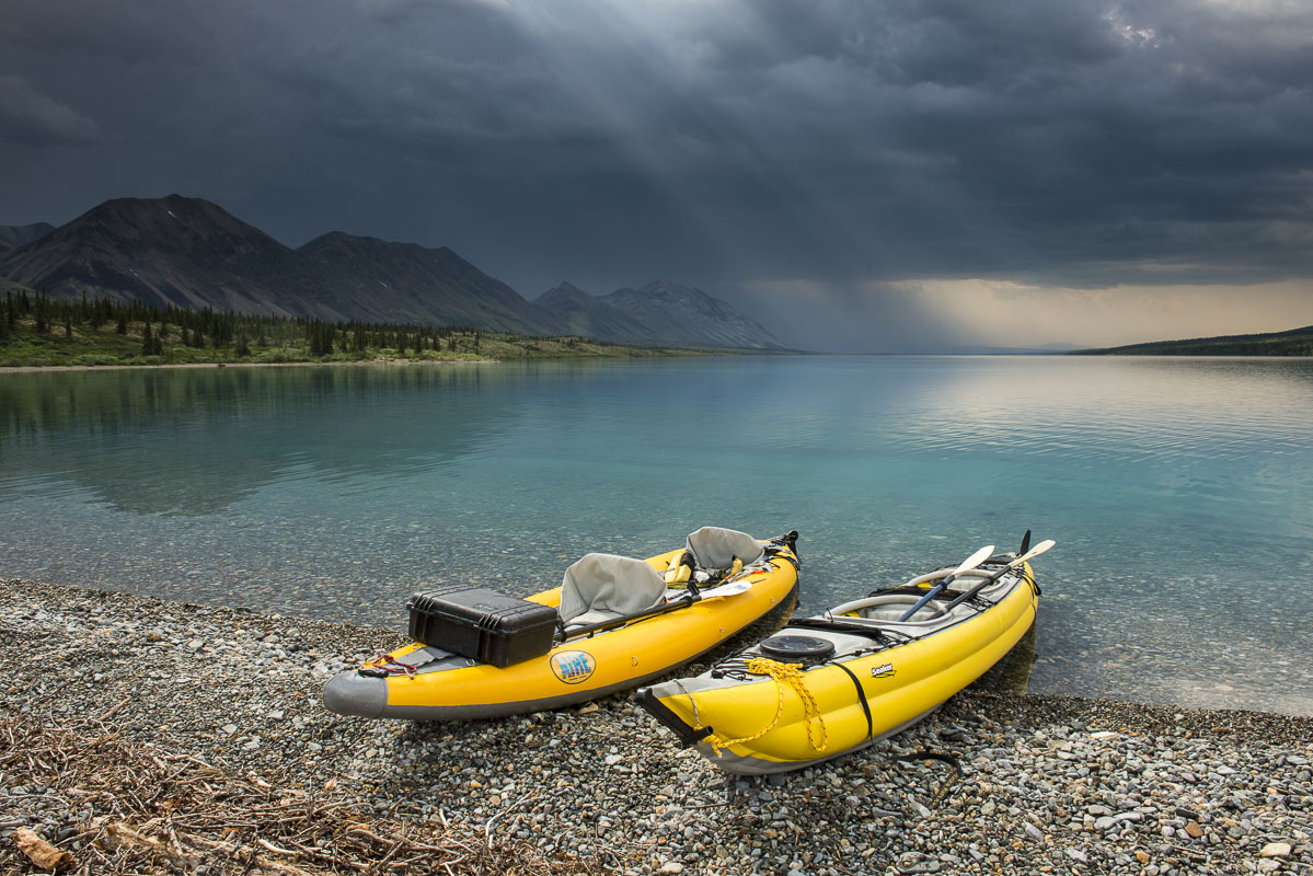 A pair of yellow kayaks rest on a beach on lower Twin Lake as a summer thunderstorm passes in Lake Clark National Park & Preserve...