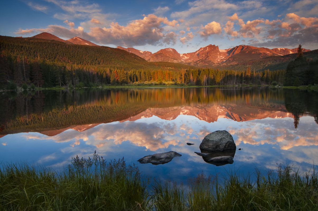 Morning light reflects on a calm Sprague Lake in Rocky Mountain National Park, Colorado.
