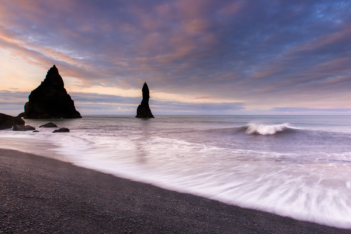 A wave crests as surf gently caresses the black beach at Reynisdrangar near Vik, Iceland.