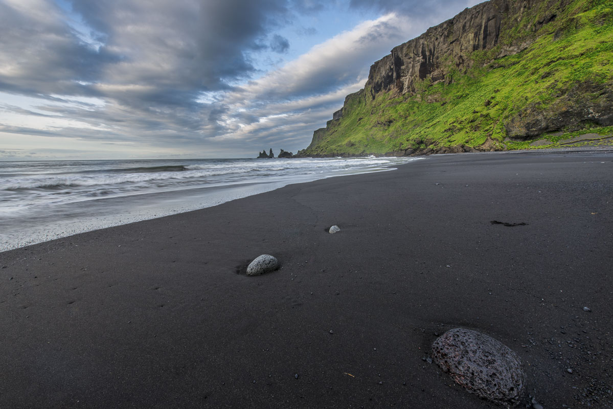 The Reynisdrangar loom in the distance at a black sand beach in Vik, Iceland.