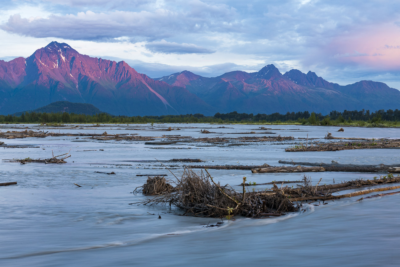 Apenglow creates a pink lighting of Pioneer Peak as the Matanuska River flows in the foreground.
