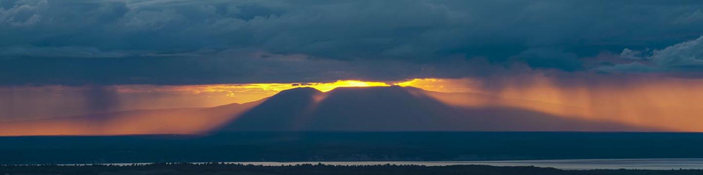The sun shines through a late summer rainstorm over Mt. Susitna (aka "Sleeping Lady") as viewed from Arctic Valley in Anchorage...