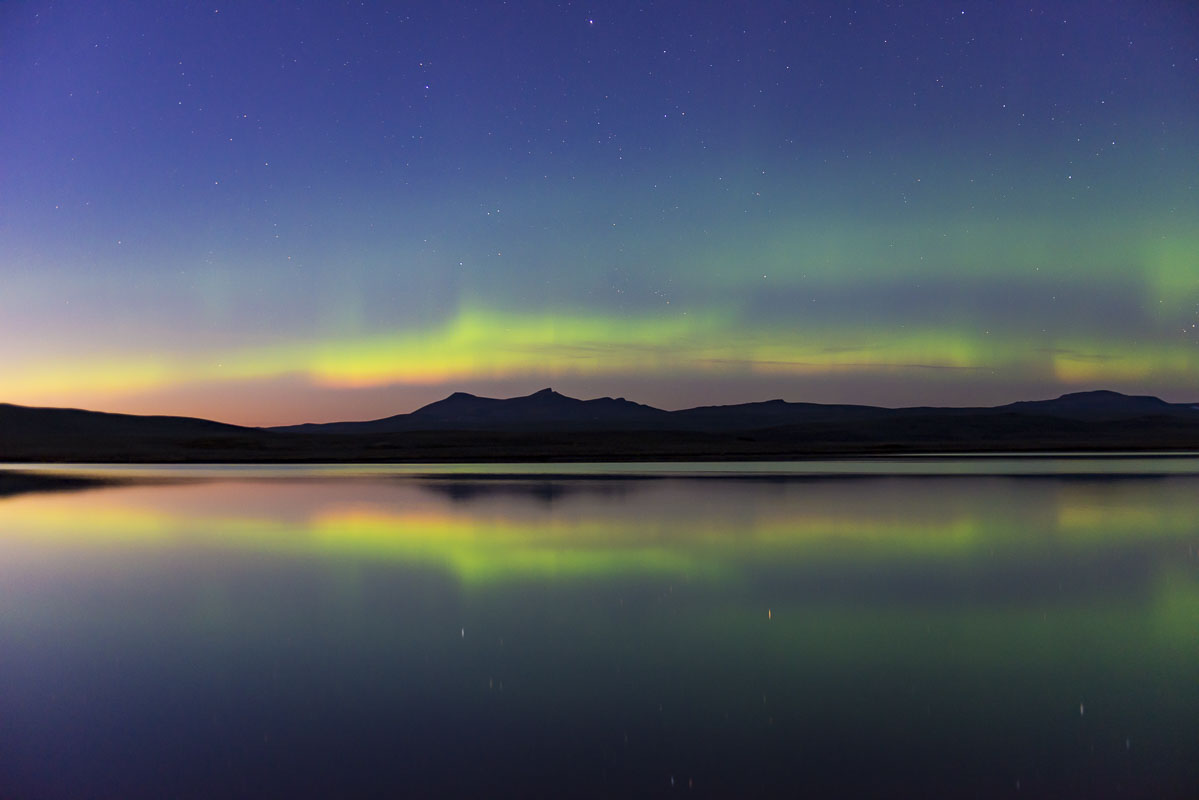 An aurora borealis display dances early in the evening and in the season in late August at Crosswinds Lake, Katmai National Preserve...