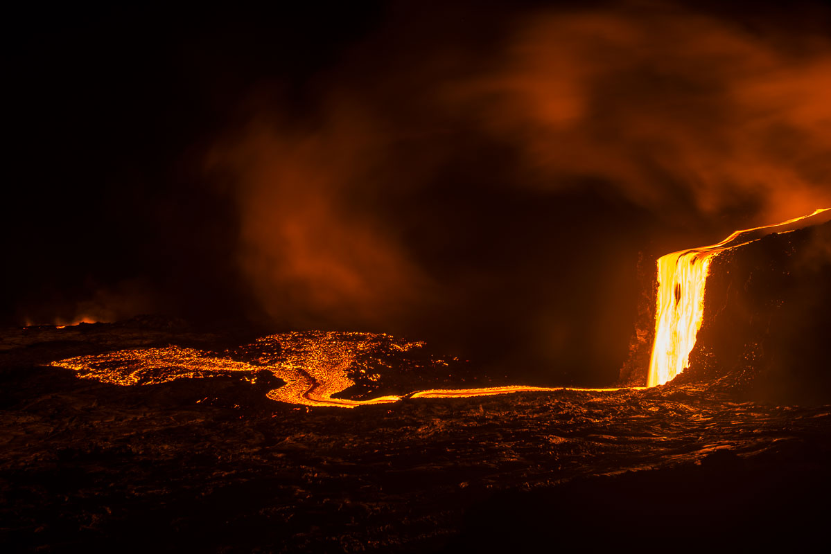 A lava fall spills off the Hawaii coast, spreading out to add new land to the island on the edge of the ocean in Hawaii Volcanoes...