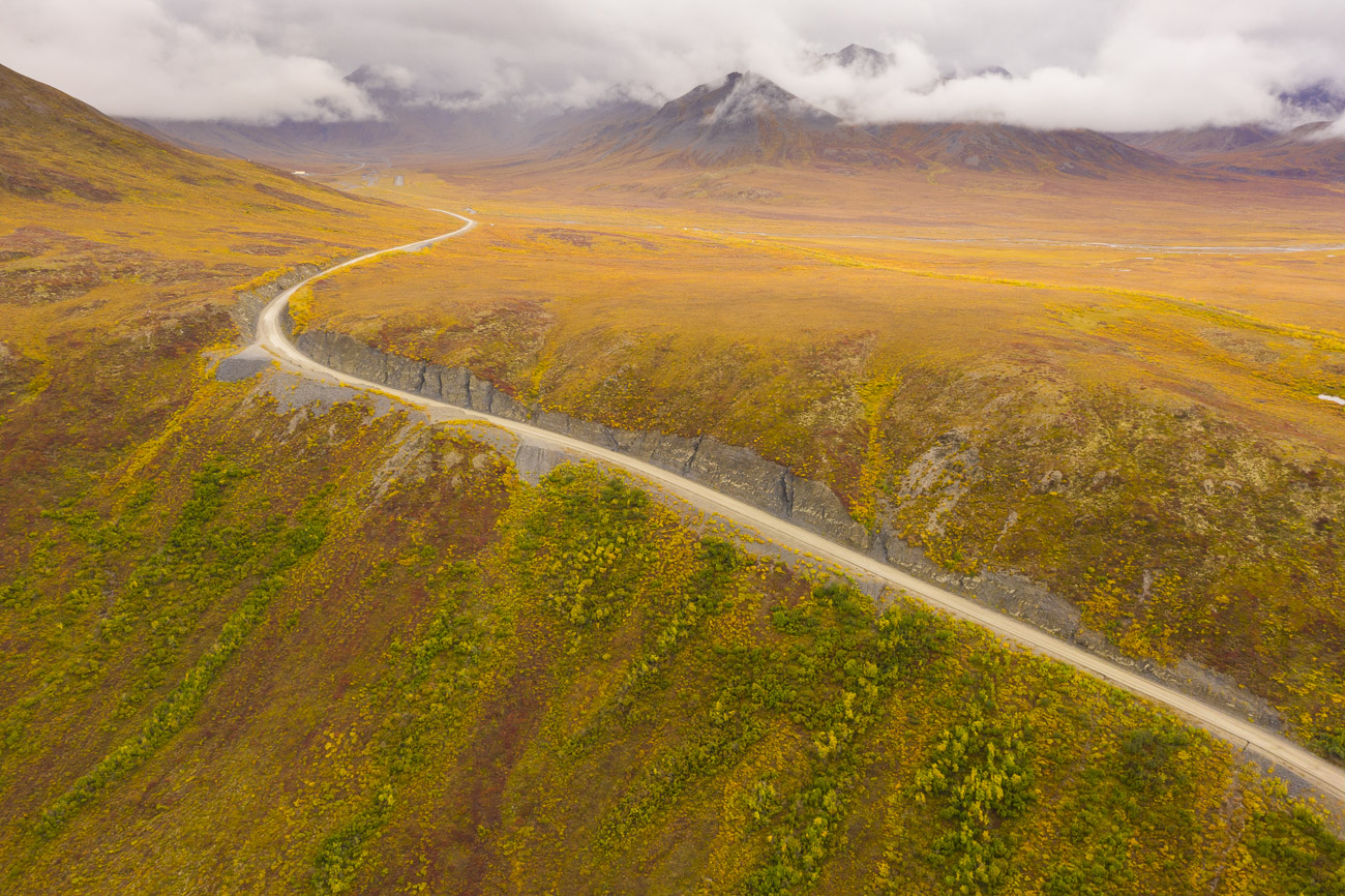 The Dalton Highway climbs up to the Chandalar Shelf as fall colors spread across the tundra.