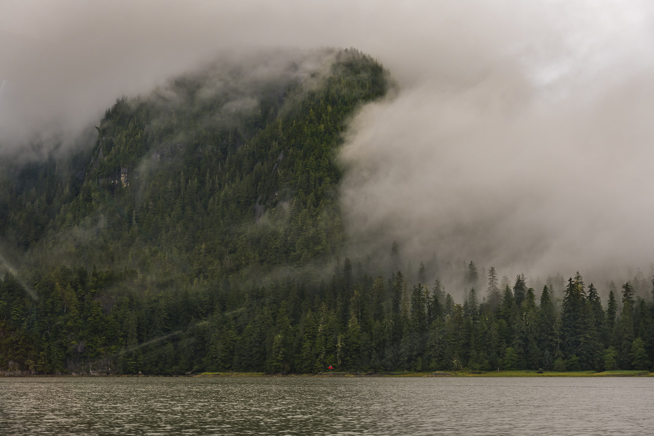 Thick clouds surrounding a mountain ridge break briefly to reveal part of the mountain, while still clinging to the rest of the...