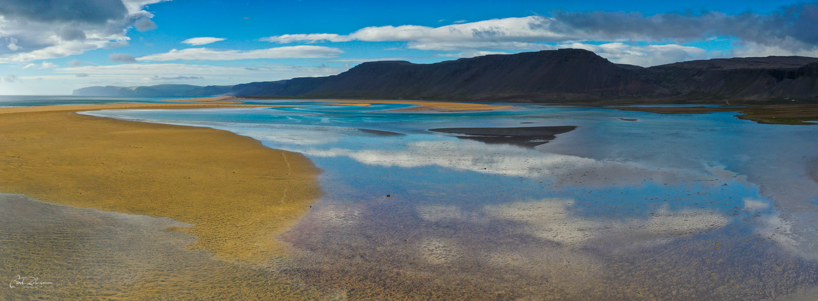 Clouds and sky reflect on waters at Rauðisandur in the Westfjords of Iceland.
