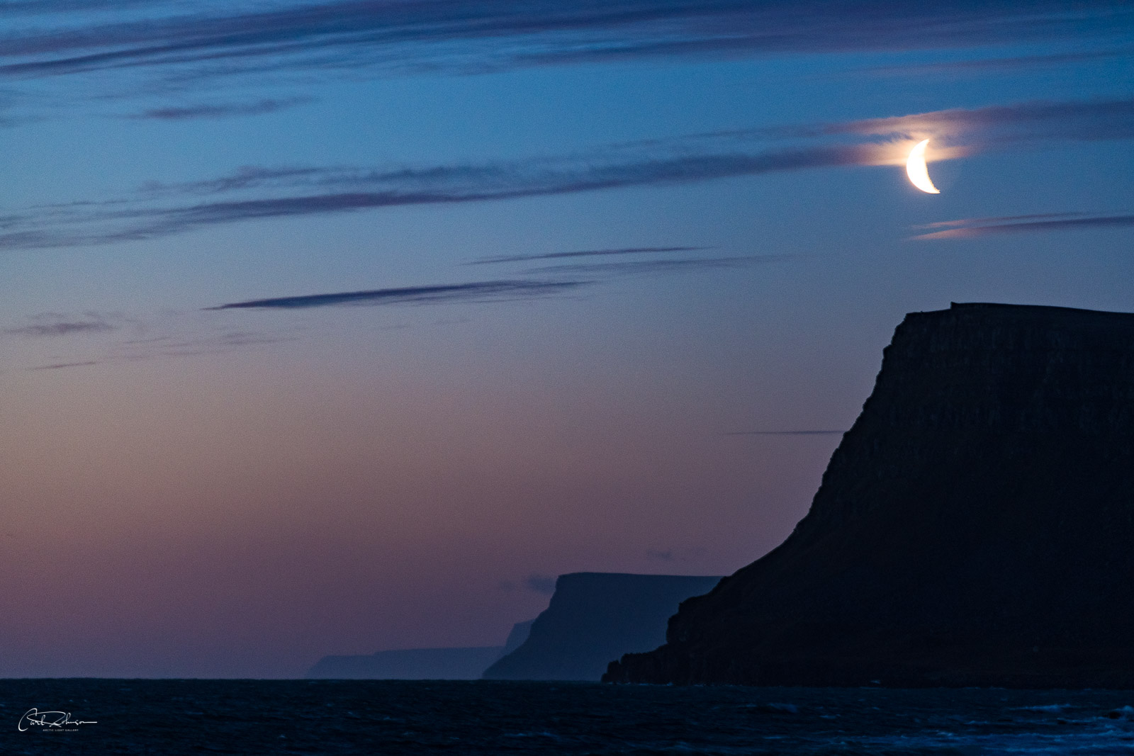 The moon rises over a series of cliffs on the west coast of Iceland near Ásgarður.