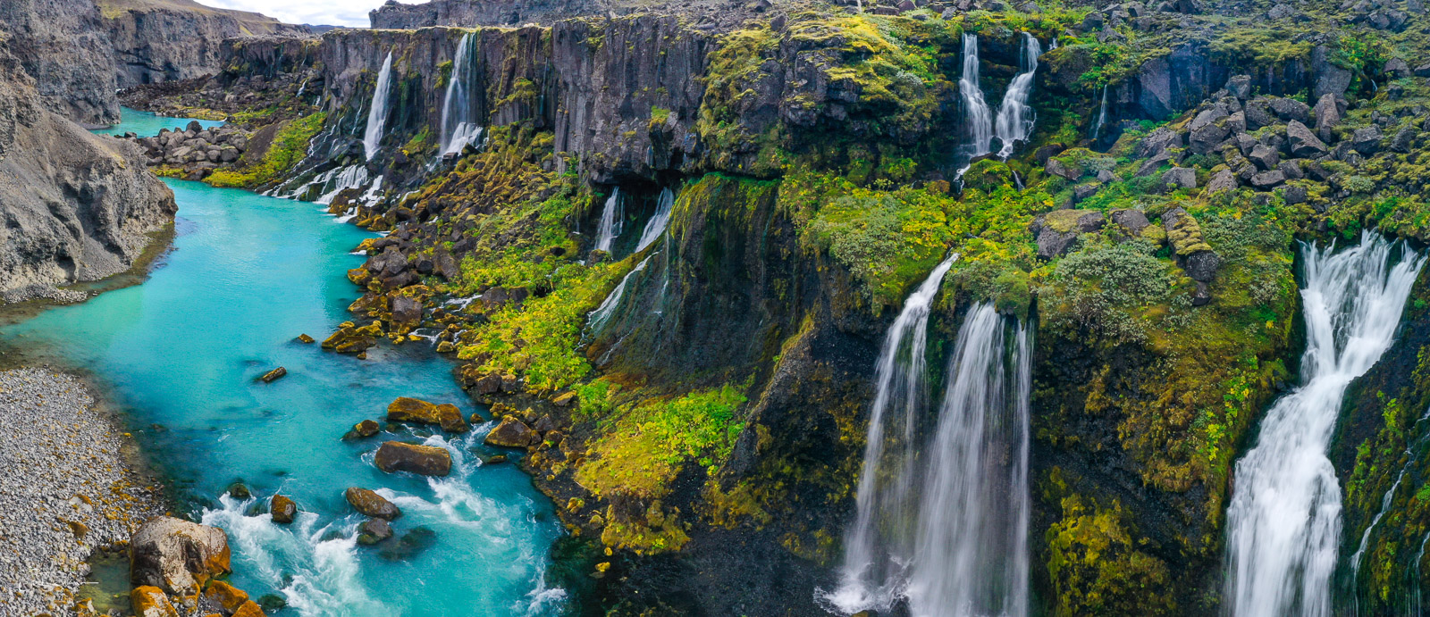 A series of waterfalls spill down into a canyon in the Iceland Highlands.