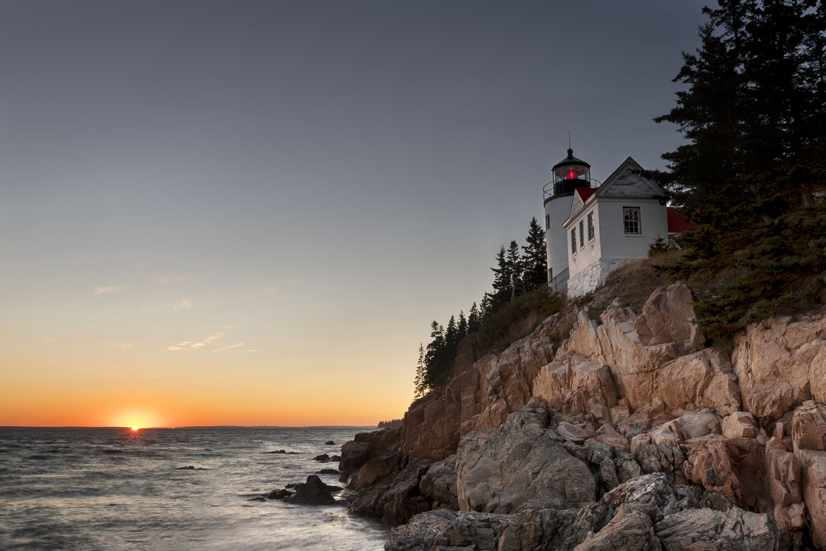 The sun dips below the horizon in autumn at the Bass Harbor Head Lighthouse, Acadia National Park, Maine.
