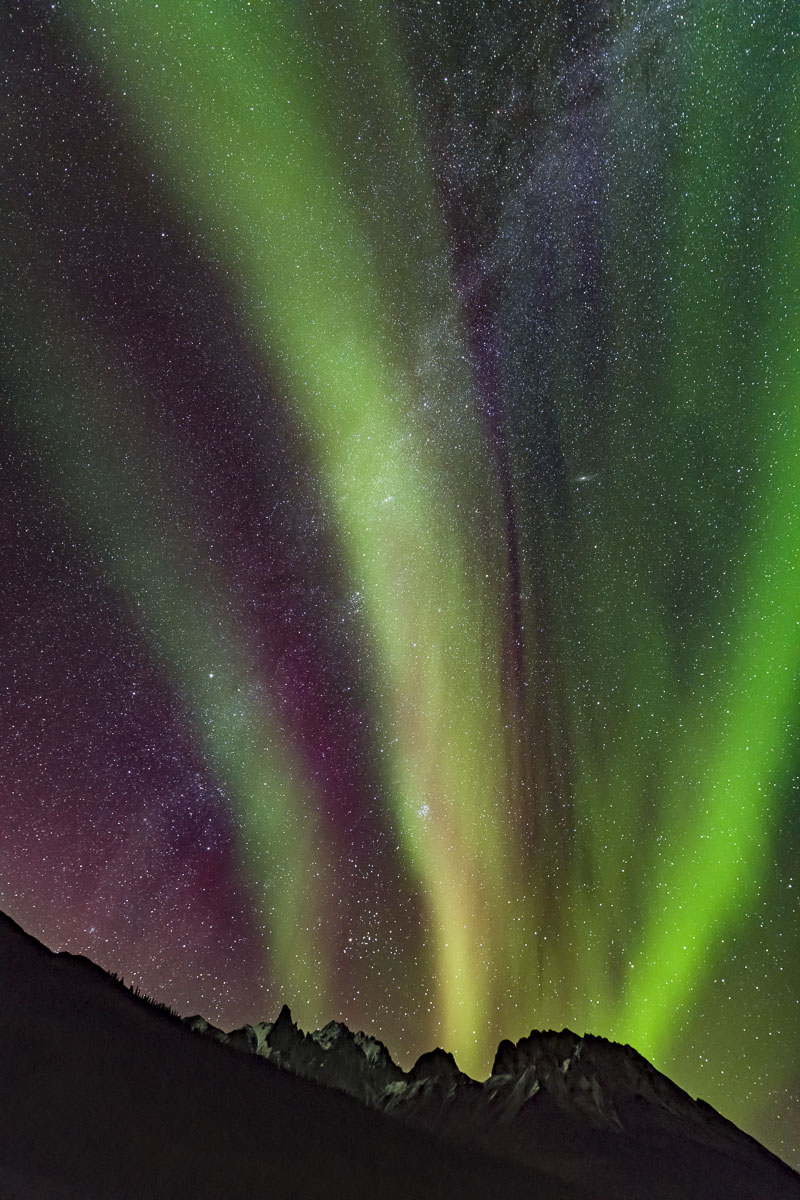 A rising aurora borealis crosses the Milky Way over peaks in the Brooks Range north of Wiseman, Alaska, along the Dalton Highway...