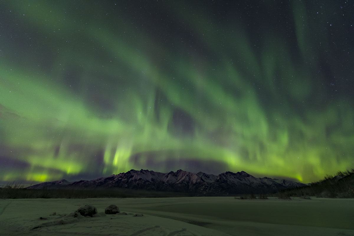 The northern lights scatter across the sky over the Knik River in early winter.