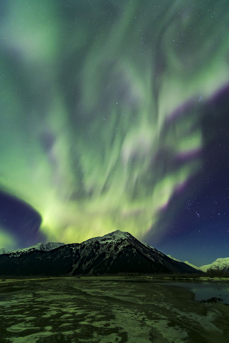 The aurora borealis seems to erupt over a mountain in Chugach National Forest during an early winter display.