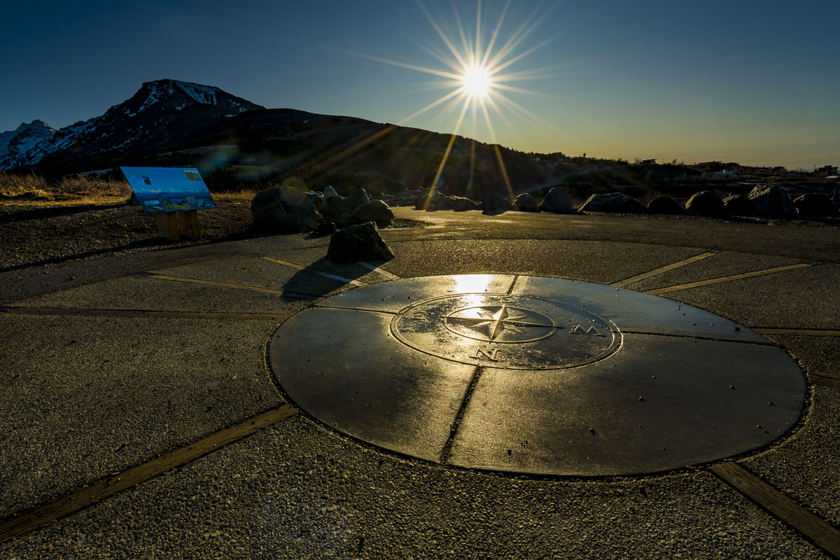 Evening sun shines behinid Flattop Mountain, reflecting on the nautical compass at the overlook.