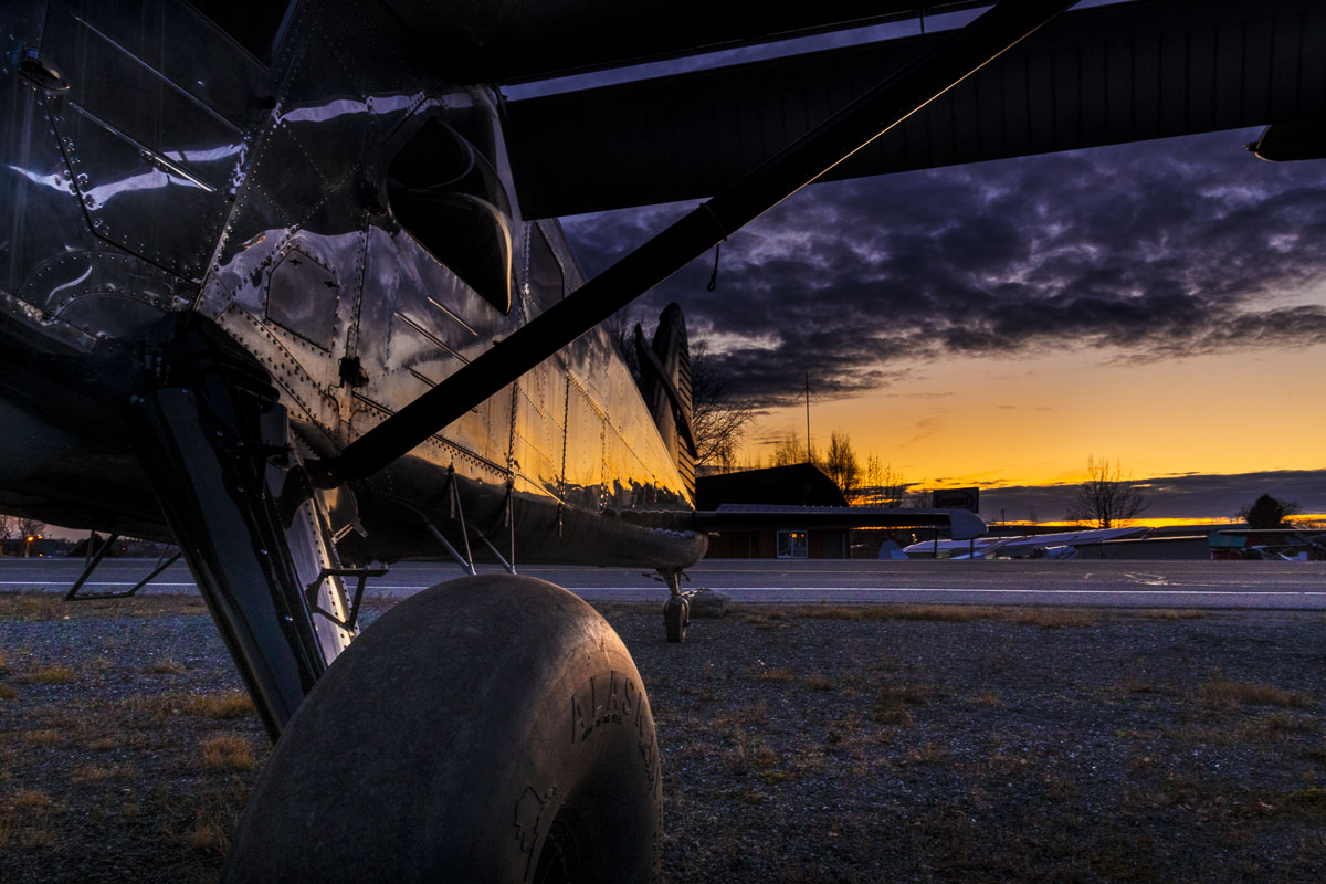 The colors of dusk reflect on the side of a bare metal small plane at the Lake Hood Seaplane Base in Anchorage.