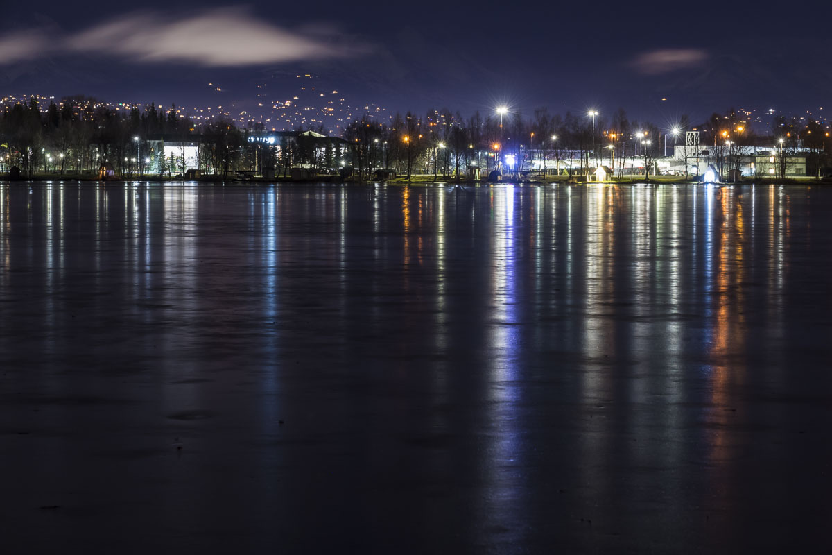 The frozen waters of Lake Spenard reflect shoreside lights in early winter.